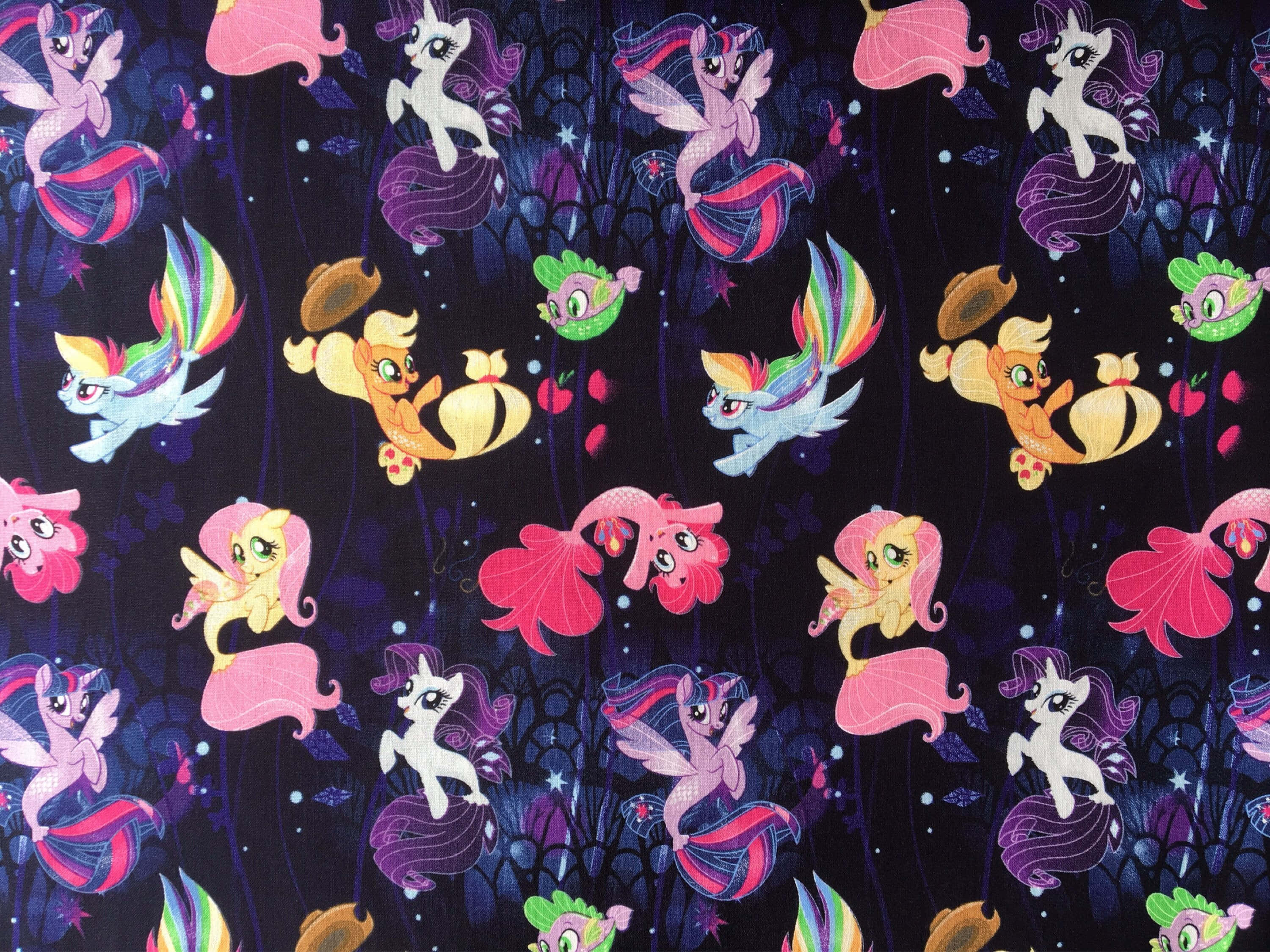 pony 桌布 壁紙 — 色彩繽紛的 My Little Pony 角色帶著美人魚尾巴在深藍色布料上於發光的珊瑚和星星之間游泳。