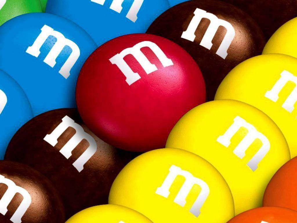 Chocolate 桌布 壁紙 — 色彩繽紛的M&M's糖果特寫，帶有白色「m」標誌，展現鮮豔的紅色、藍色、黃色、棕色和綠色色調。