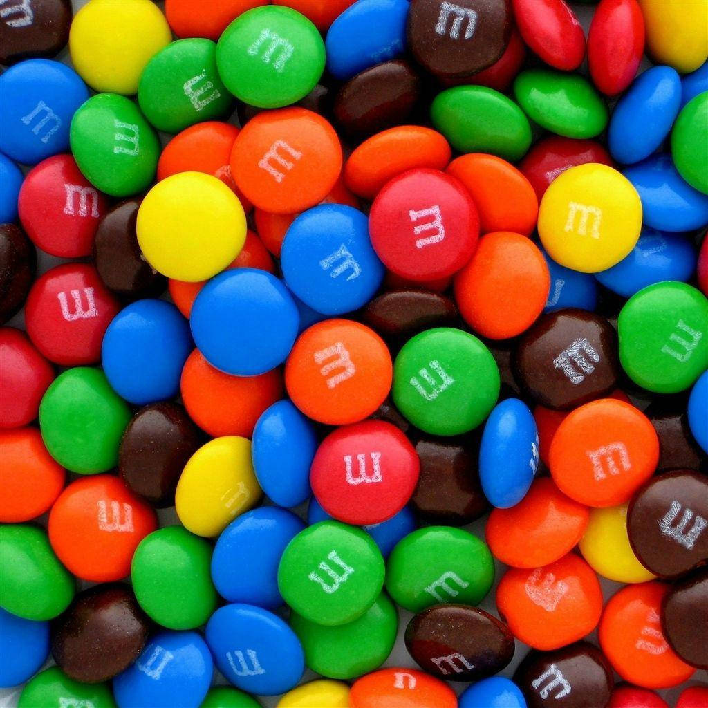 朱古力 桌布 壁紙 — 色彩繽紛的M&M's糖果特寫，白色「m」標誌密集散落。