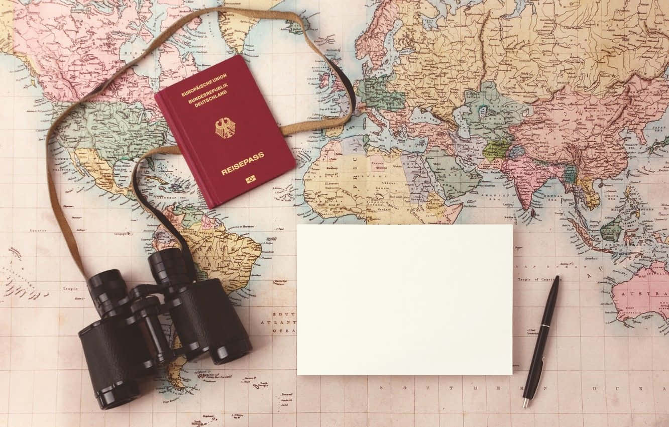 用於旅行規劃的復古世界地圖上的紅色護照、望遠鏡和筆。