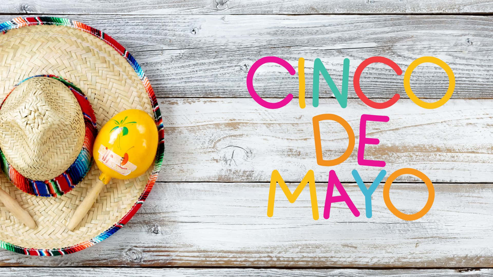 色彩繽紛的五月五日慶祝活動 壁紙 — 色彩繽紛的 Cinco de Mayo 文字和節日墨西哥帽及沙槌在風化木板上。