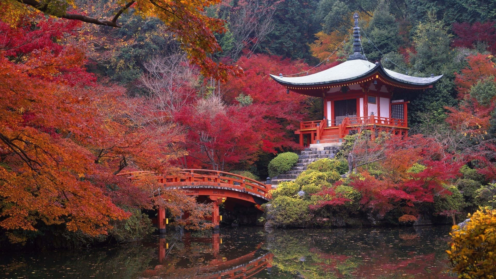 紅色橋樑和寺廟，周圍環繞著秋葉，倒映在水中。