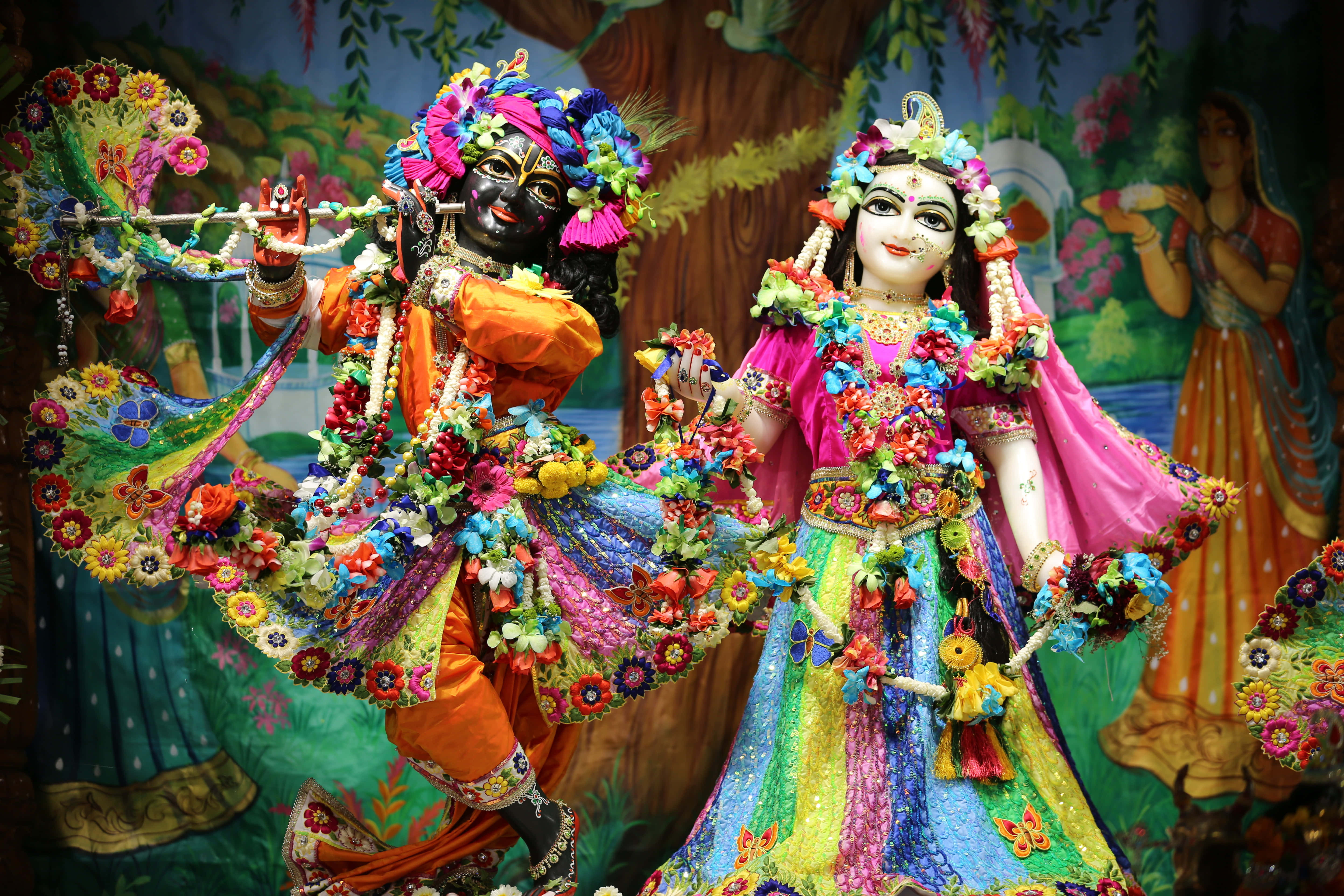 Radha Krishna 桌布 壁紙 — 色彩繽紛的克里希納和拉達雕像裝飾著鮮花和充滿活力的傳統服飾，一起跳舞。