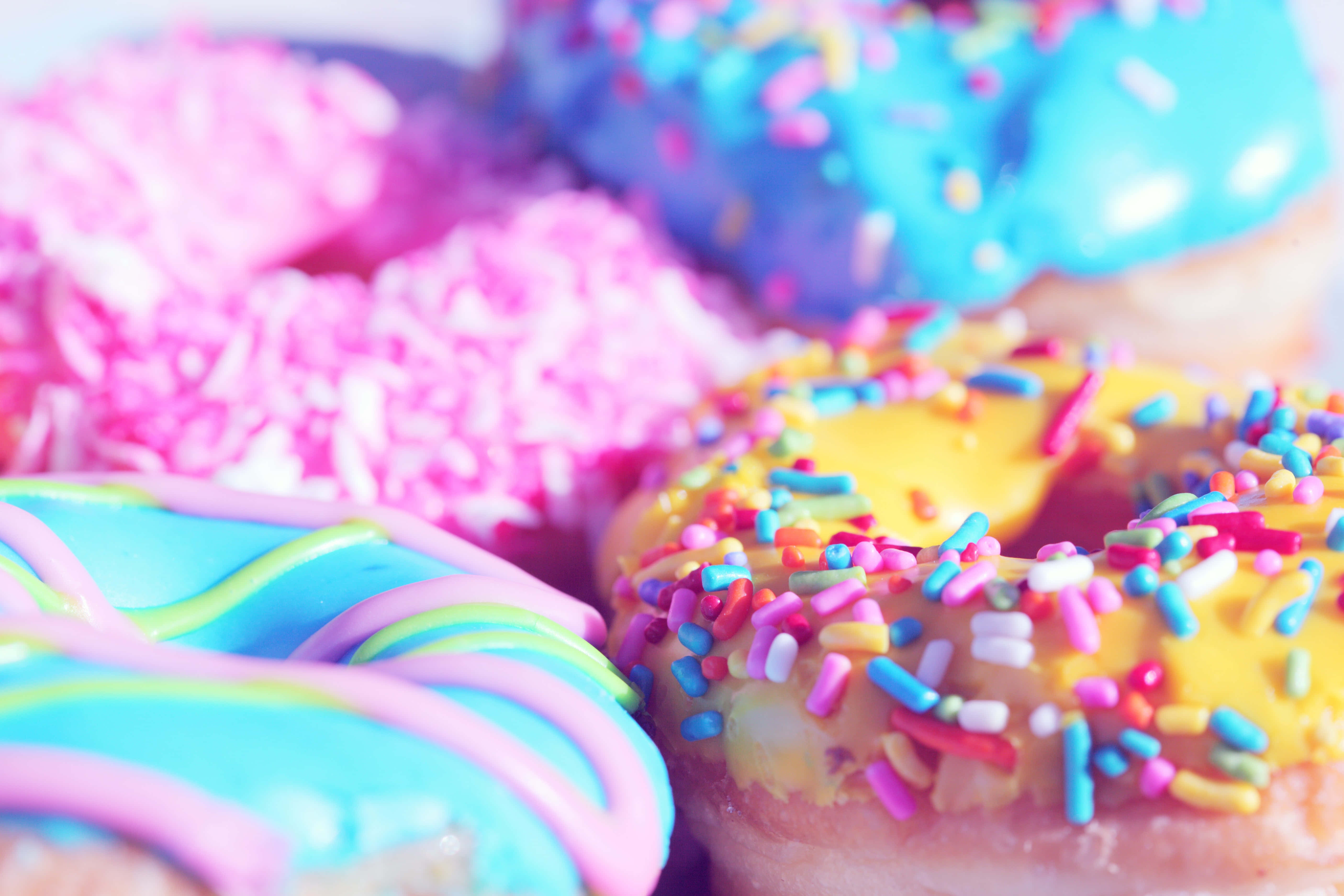 Cute Donut 桌布 壁紙 — 色彩繽紛的冬甩特寫，帶有鮮豔的糖霜和彩虹糖針，營造出甜美的節日美食。