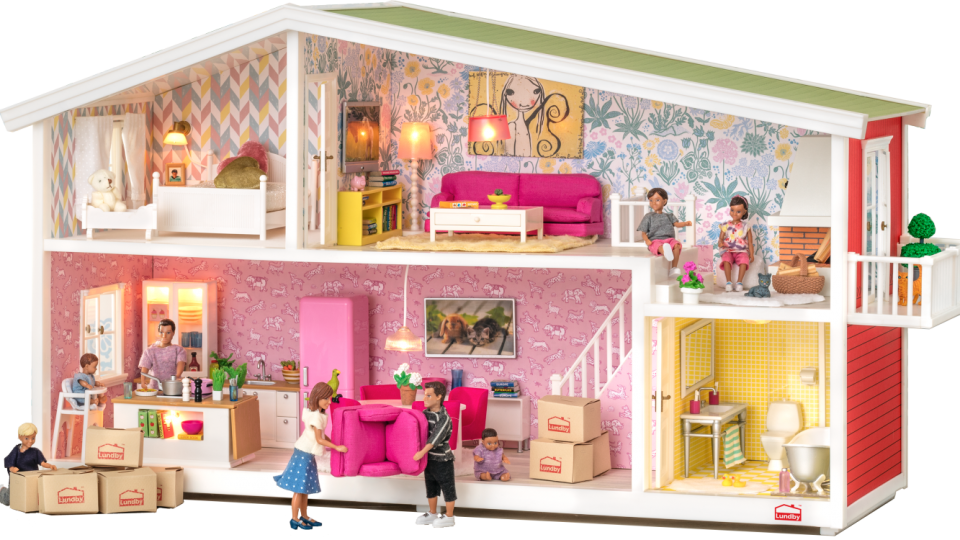 色彩繽紛的娃娃屋內景遊戲場景 壁紙 — 一個色彩繽紛的娃娃屋，裡面有微型人物在充滿活力的粉紅色和黃色內飾中搬入並拆箱。