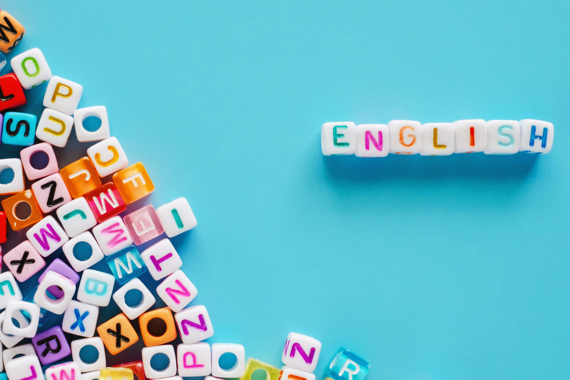 English 桌布 壁紙 — 色彩繽紛的字母方塊在純藍色背景上拼出「ENGLISH」，並散落著字母瓷磚。