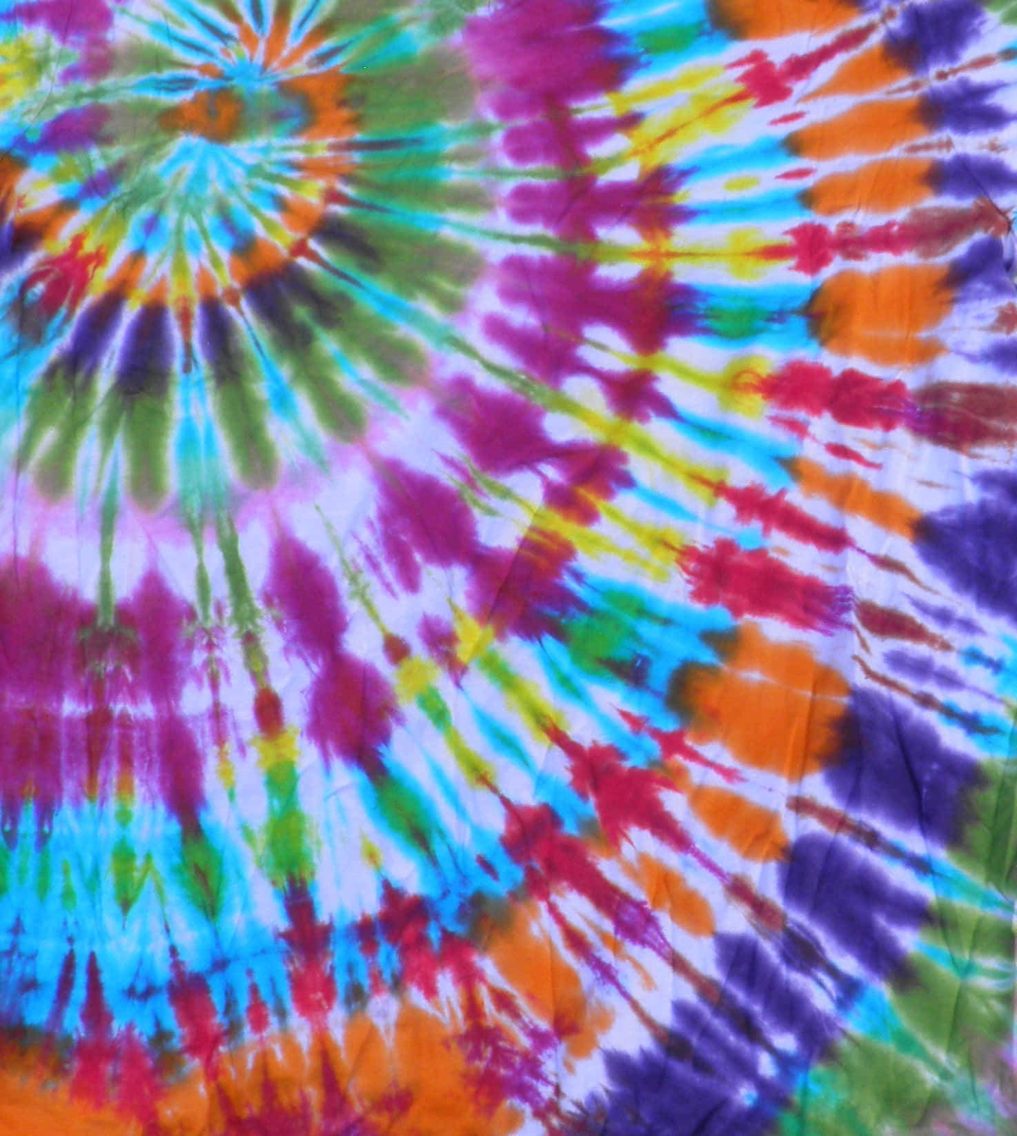 Purple Tie Dye 桌布 壁紙 — 色彩繽紛的彩虹紮染布料，漩渦圖案從中心點向外擴散。