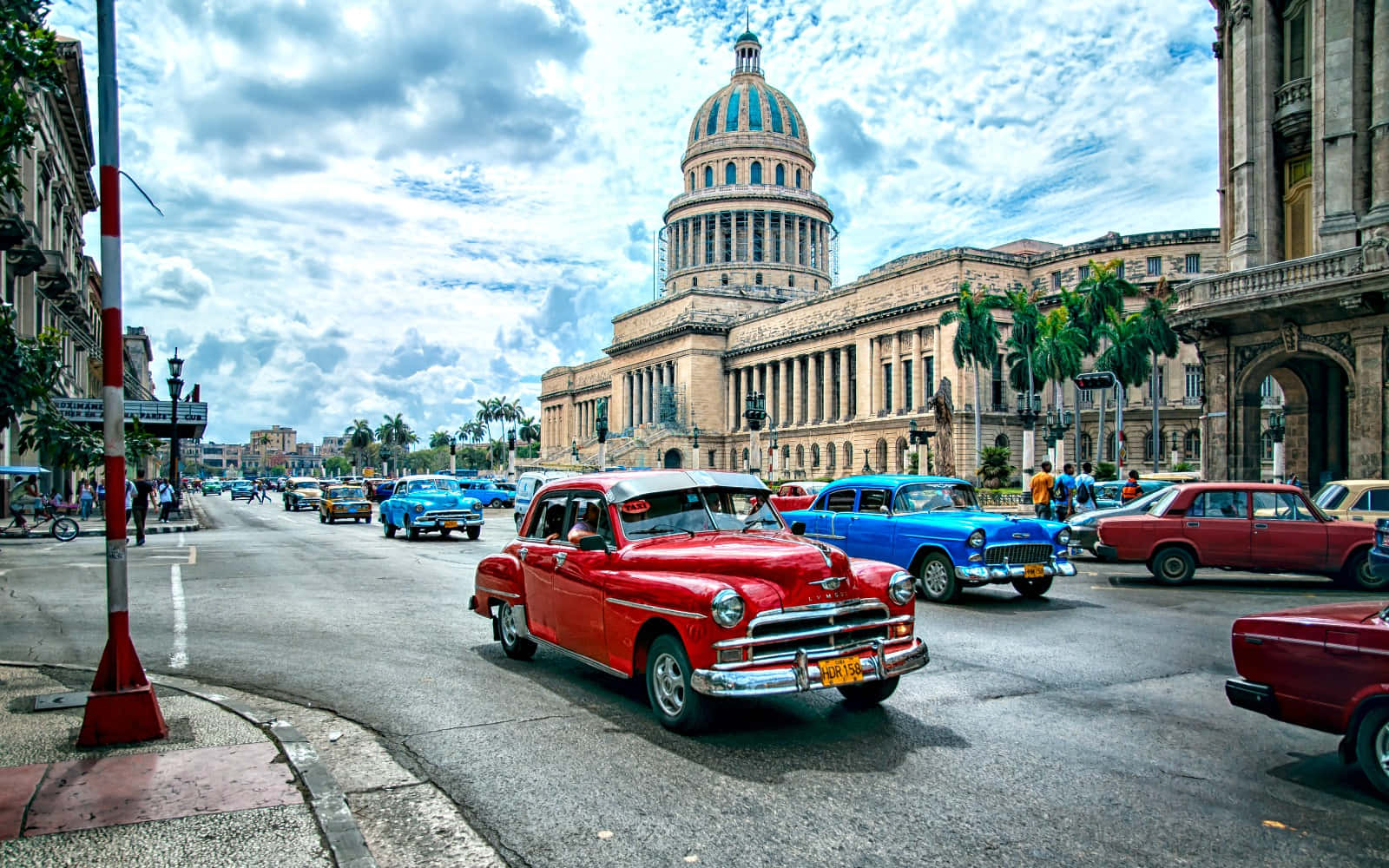 Cuba 桌布 壁紙 — 色彩繽紛的復古汽車在哈瓦那多雲的天空下駛過宏偉的國會大廈。