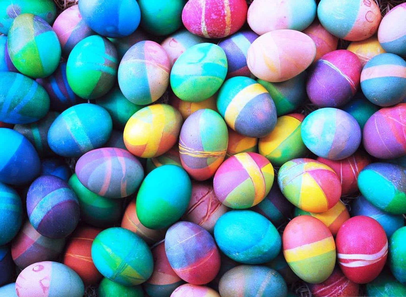 Pastel Easter 桌布 壁紙 — 色彩繽紛的手繪復活節彩蛋，帶有彩虹條紋和漩渦，緊密地堆疊在一起的鮮明特寫。
