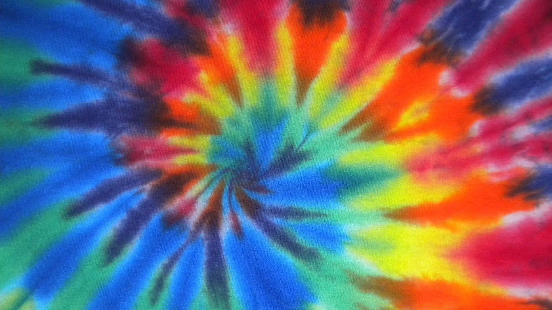 色彩繽紛的扎染液滴 壁紙 — 充滿活力的螺旋紮染圖案從中心點向外輻射，帶有鮮明的藍色、紅色、黃色和綠色。