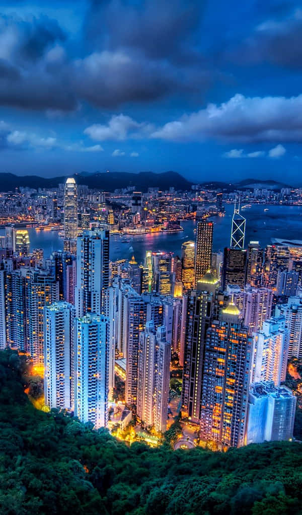 色彩繽紛的抽象畫作 壁紙 — 香港天際線的壯麗黃昏景色，摩天大樓閃爍光芒，港口在戲劇性的藍天下。