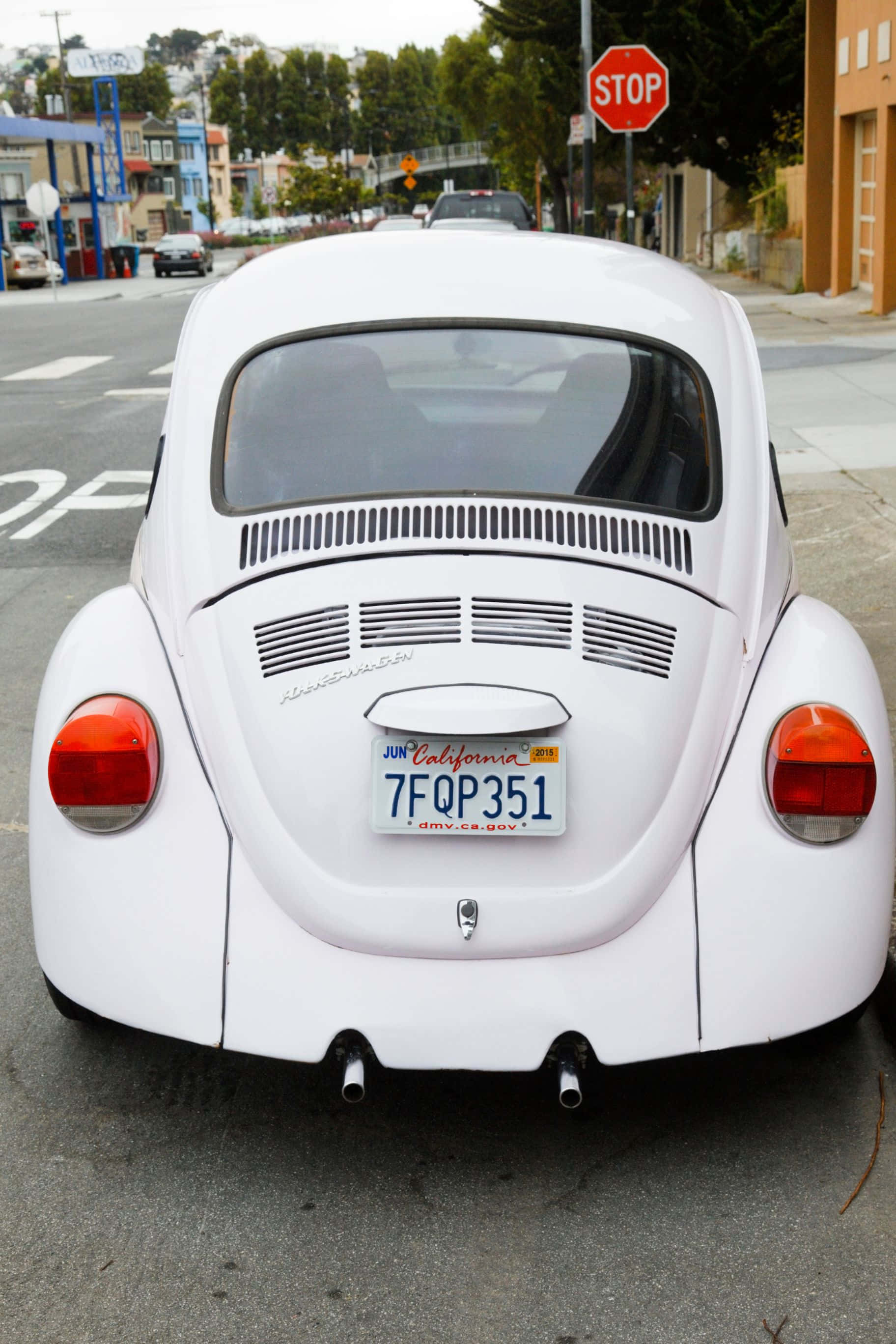 色彩繽紛的抽象藝術 壁紙 — 從後方觀看一輛完美無瑕的白色 vintage Volkswagen Beetle 停泊在城市的街道上，背景有停車標誌和色彩繽紛的建築物。