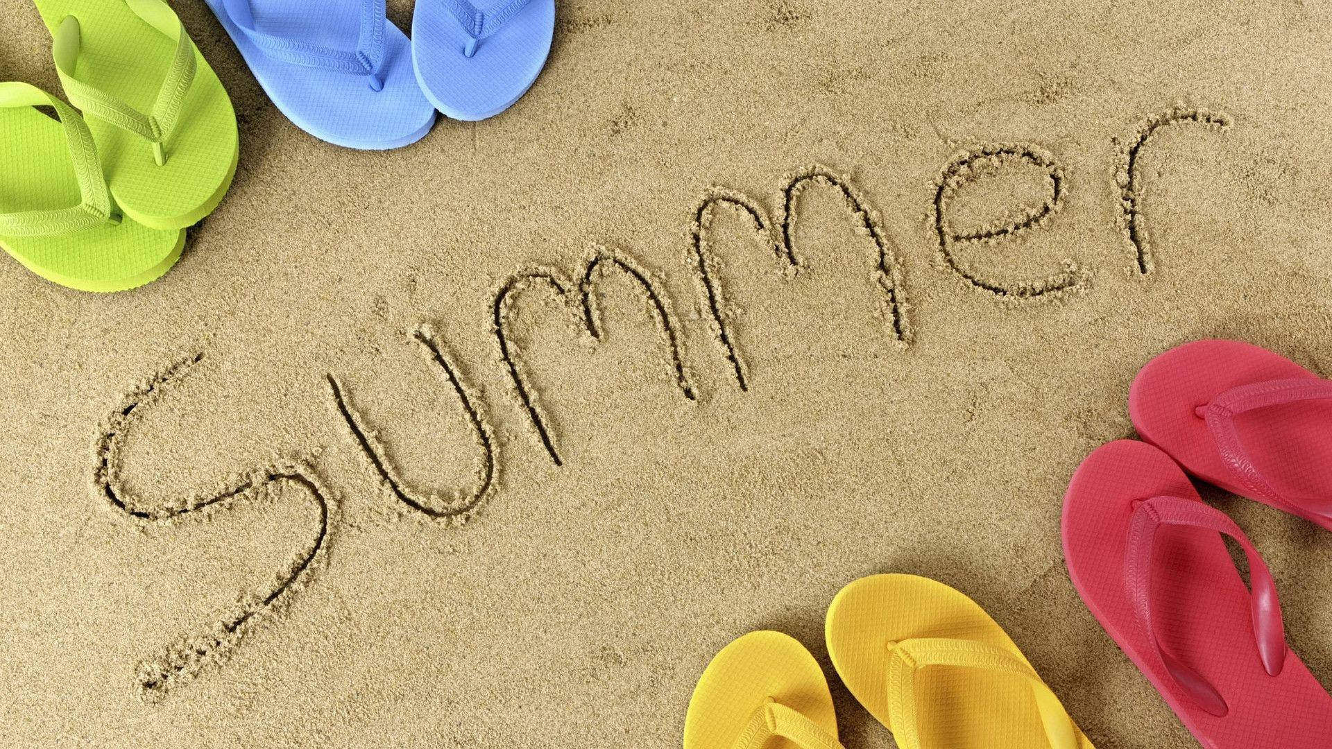 Summer Beach 桌布 壁紙 — 色彩繽紛的拖鞋圍繞著沙灘上寫著的「Summer」字樣，營造出海灘度假的氛圍。