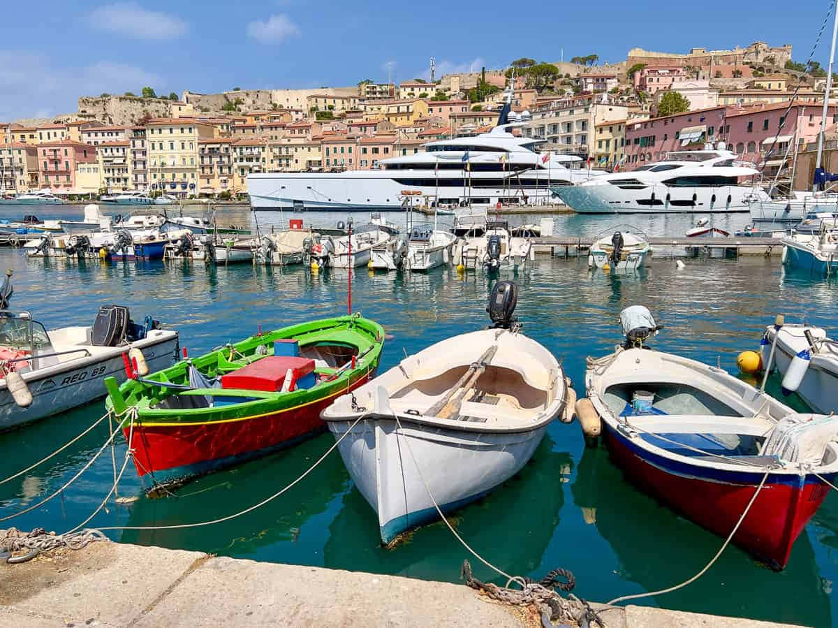 Italian Island 桌布 壁紙 — 色彩繽紛的漁船在陽光明媚的港口輕輕搖晃，豪華遊艇和赤陶屋頂的建築物沿著山坡攀升。