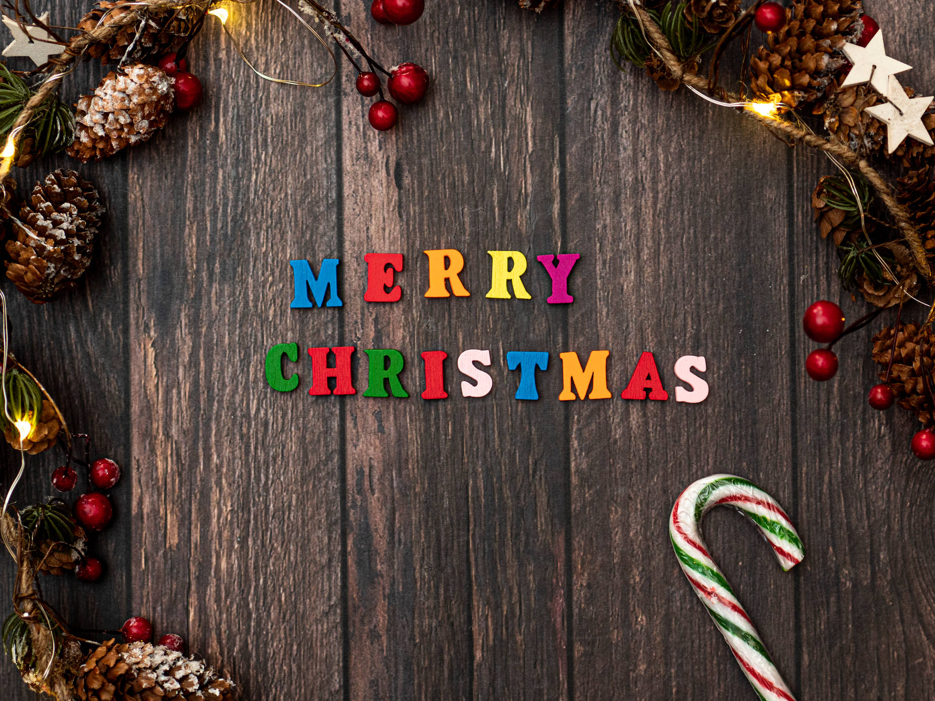 Merry Christmas 以彩色字母拼寫在木質背景上，帶有節日裝飾。
