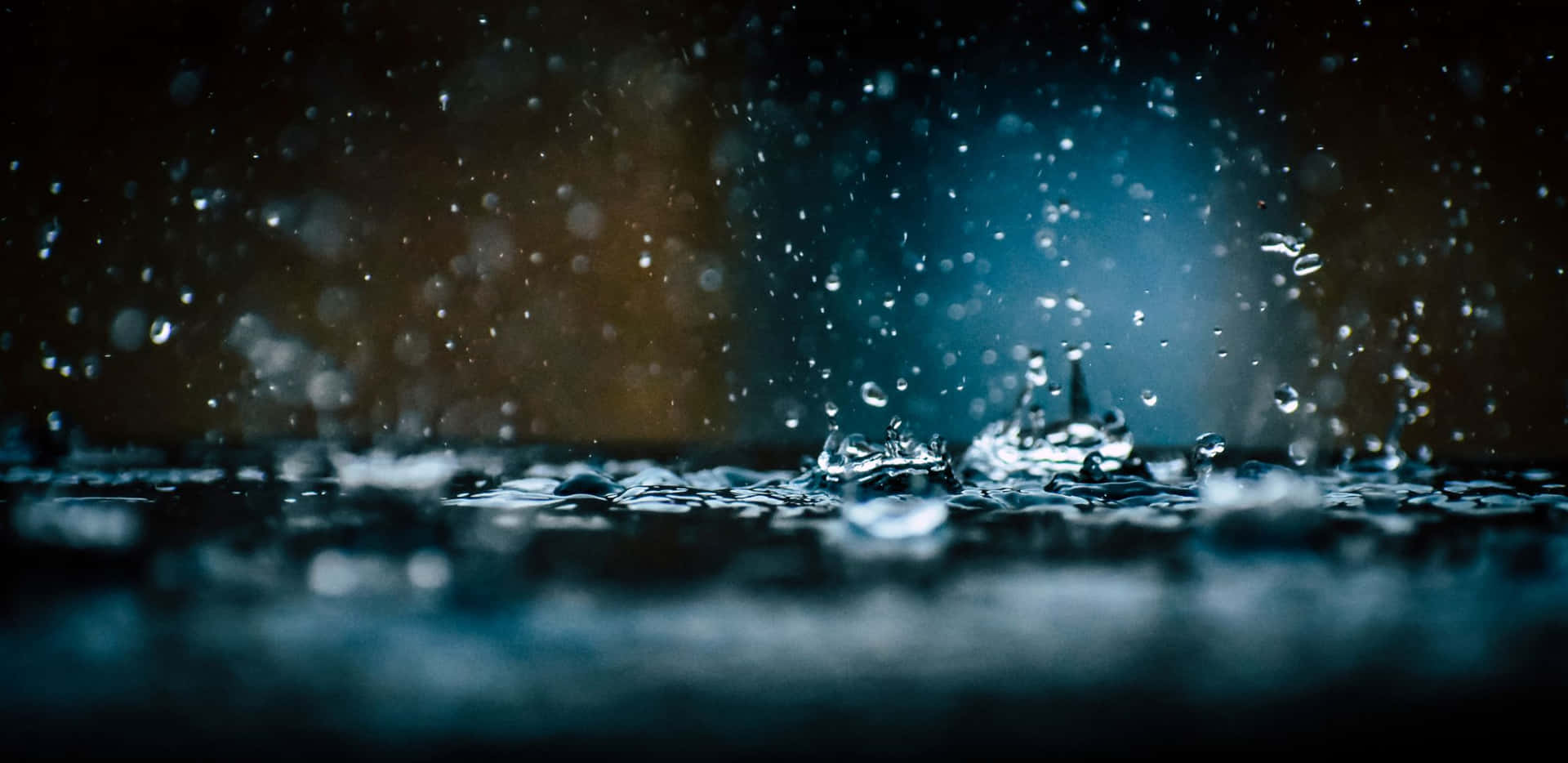 夜間雨滴在潮濕表面上飛濺的特寫。