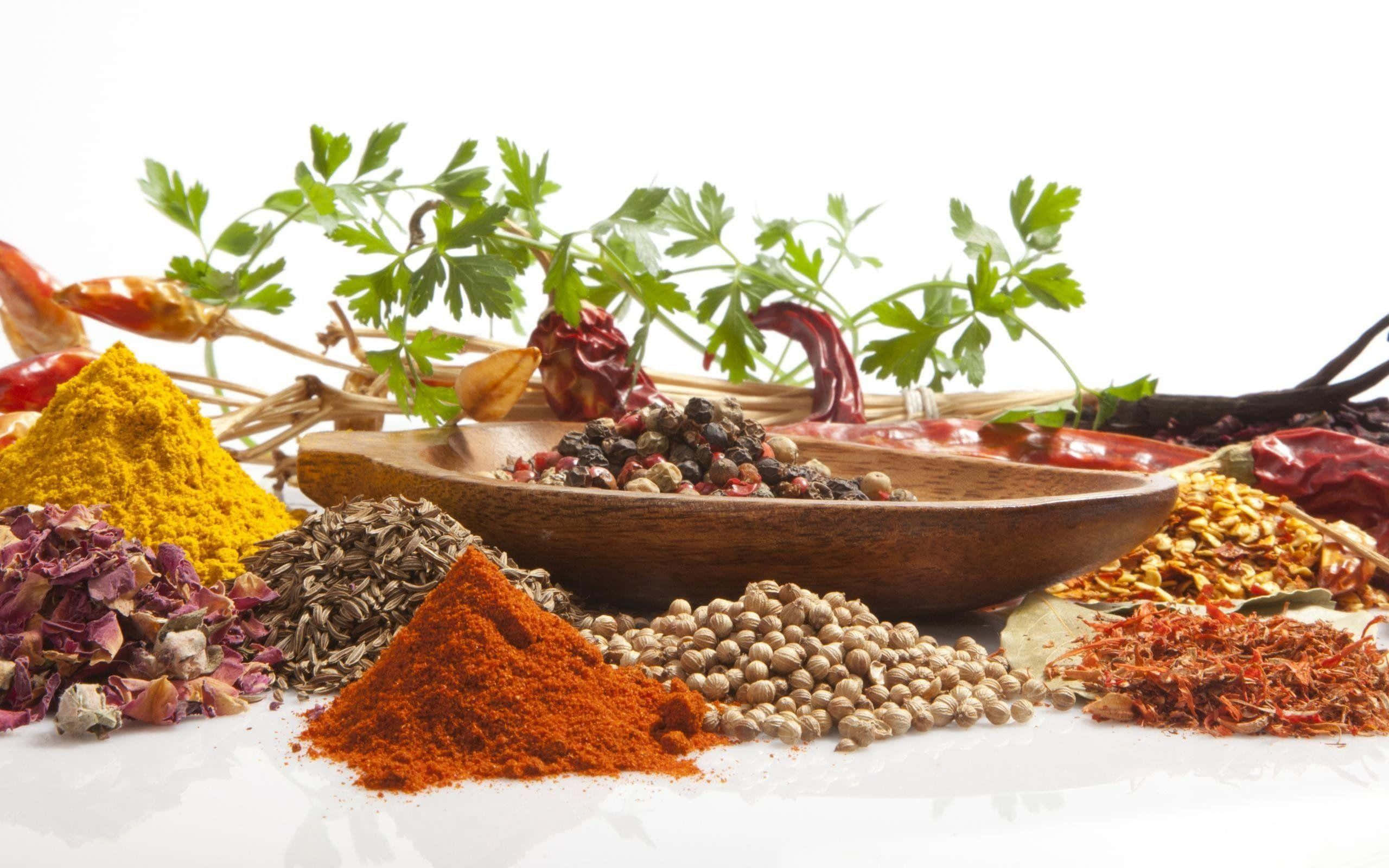 Spices 桌布 壁紙 — 色彩繽紛的香料和新鮮香草堆放在白色表面上，配有一個木碗。