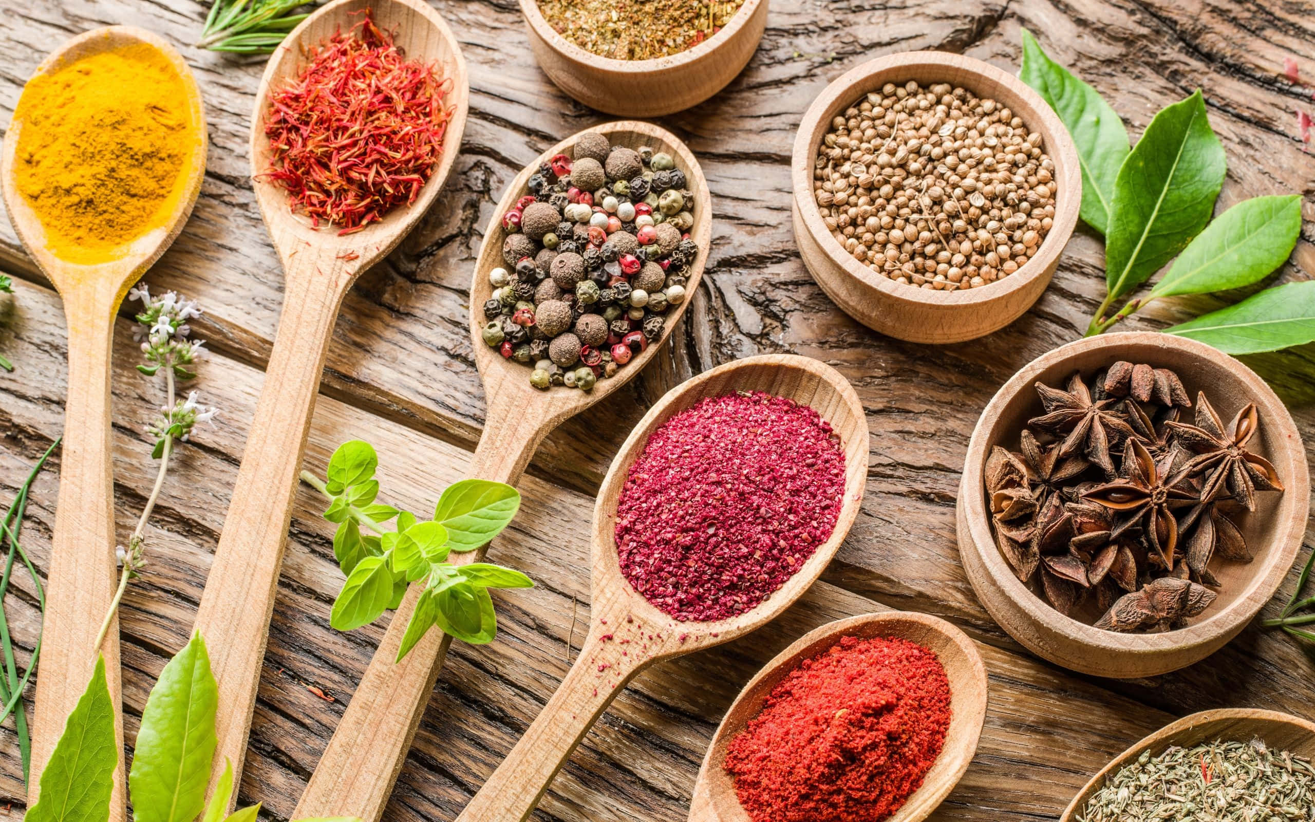 Spice 桌布 壁紙 — 色彩繽紛的香料和香草放在木勺和木碗中，擺放在質樸風化的木質表面上。