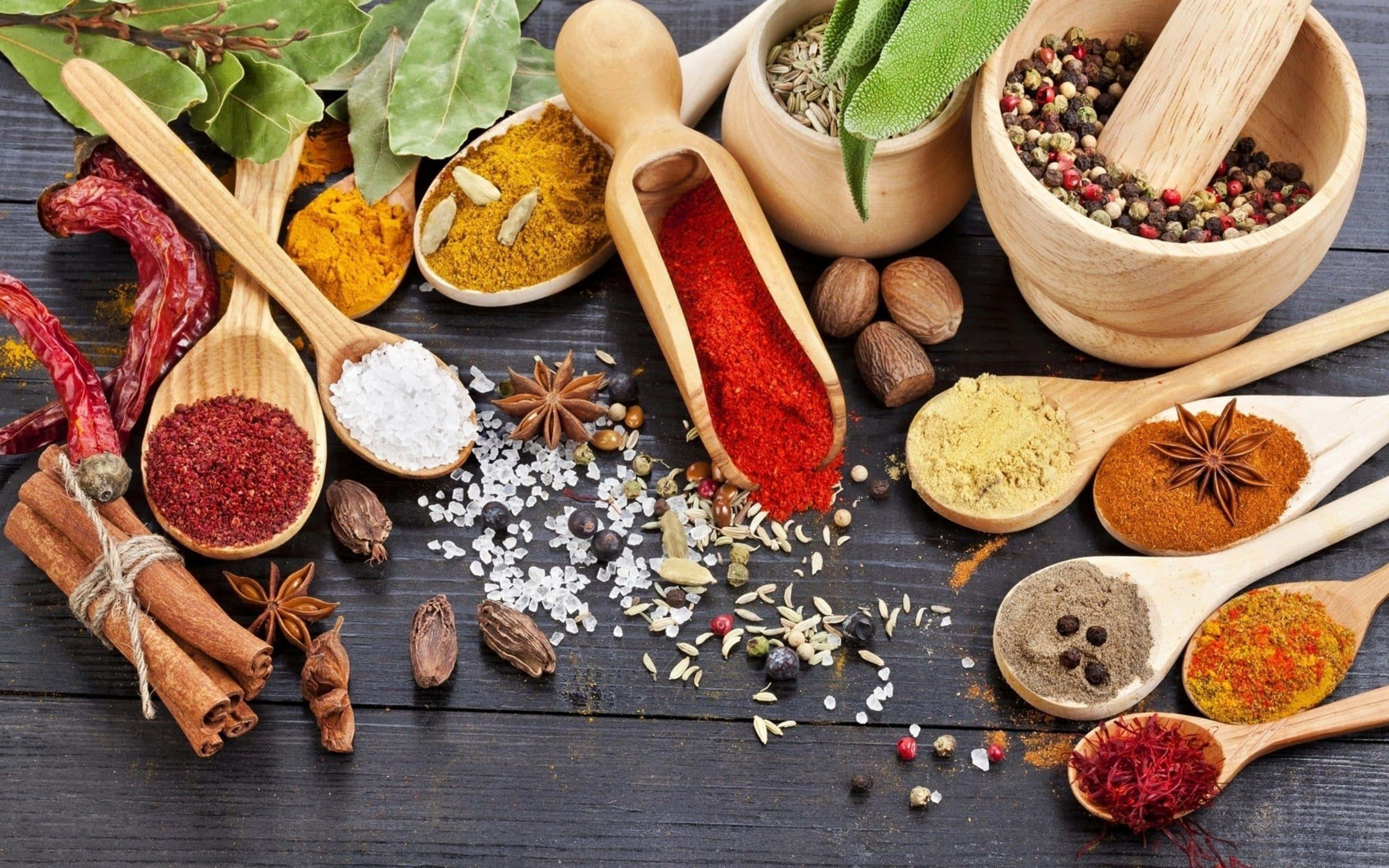 Spices 桌布 壁紙 — 色彩繽紛的香料和香草放在木勺和碗中，散落在深色鄉村風木桌上。