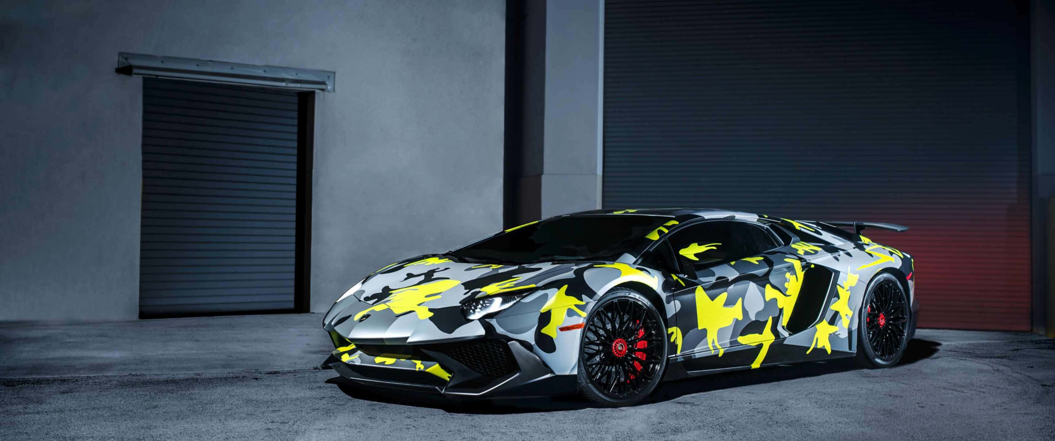 色彩飛濺 - 不是普通的蘭博基尼 壁紙 — 一輛林寶堅尼 Aventador 帶有醒目的黃色和灰色迷彩塗裝，停在昏暗的工業車庫中。