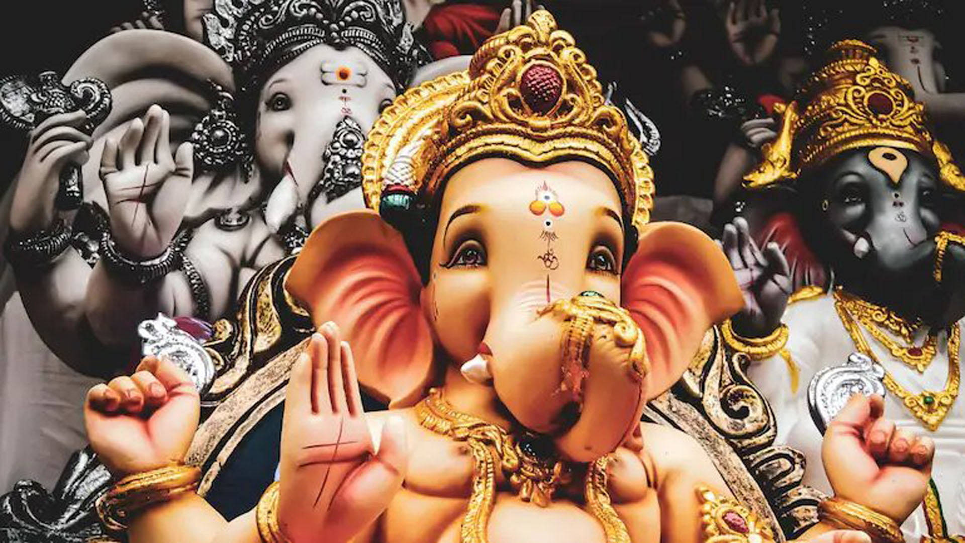 Hindu God 桌布 壁紙 — 色彩鮮豔的象頭神像，戴著金色皇冠和珠寶，周圍環繞著其他象頭神形態的黑白描繪。