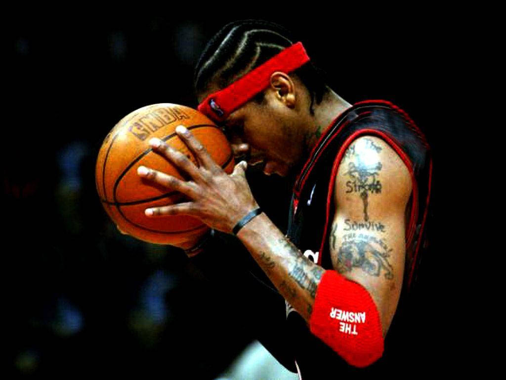 艾倫·艾弗森頭頂持球照 壁紙 — 一名有紋身和紅色頭帶的籃球運動員在緊張時刻將額頭靠在球上。