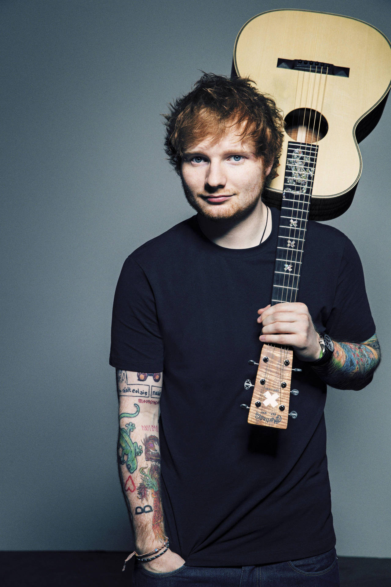 有紋身的男人拿著木結他的工作室肖像