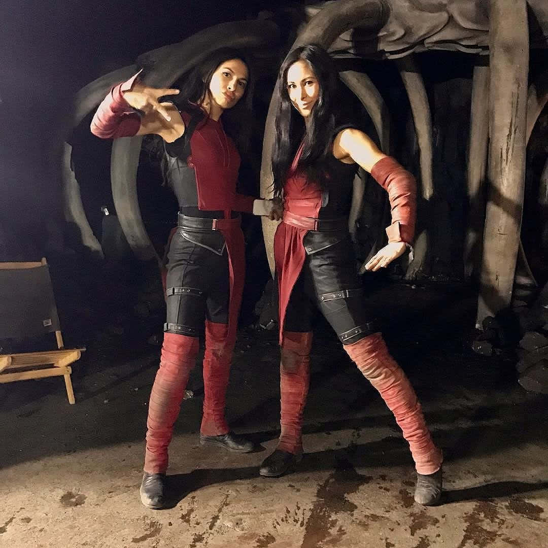 兩位身穿紅黑色服裝的cosplayer在一個巨大的頭骨道具前擺姿勢。