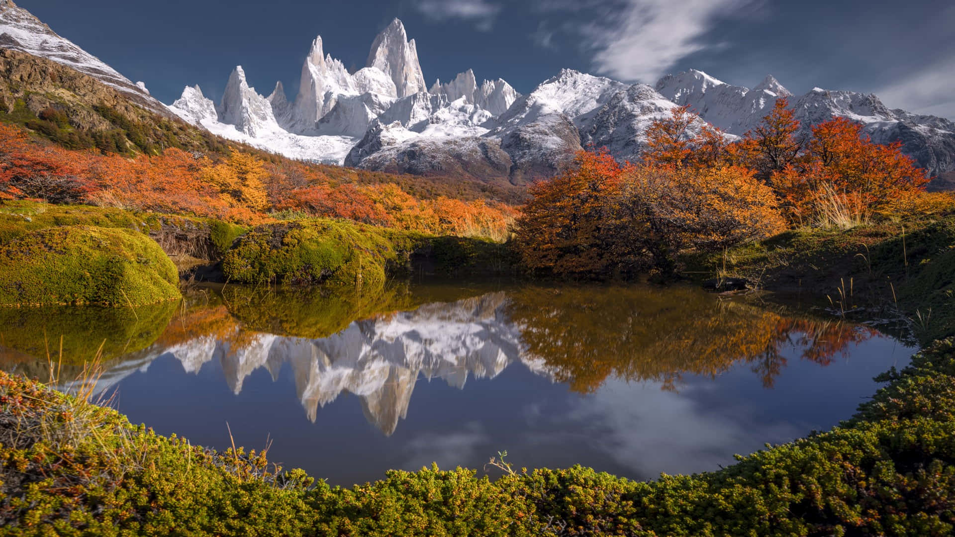 艾爾查滕的絕美風景 壁紙 — 寧靜的山湖在戲劇性的天空下映照著積雪的山峰和秋天的樹木。