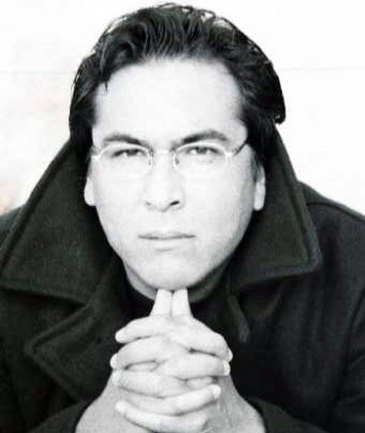 艾瑞克·施威格戴眼鏡黑白照 壁紙 — 一位戴眼鏡、雙手合十的男子直視鏡頭的黑白肖像。
