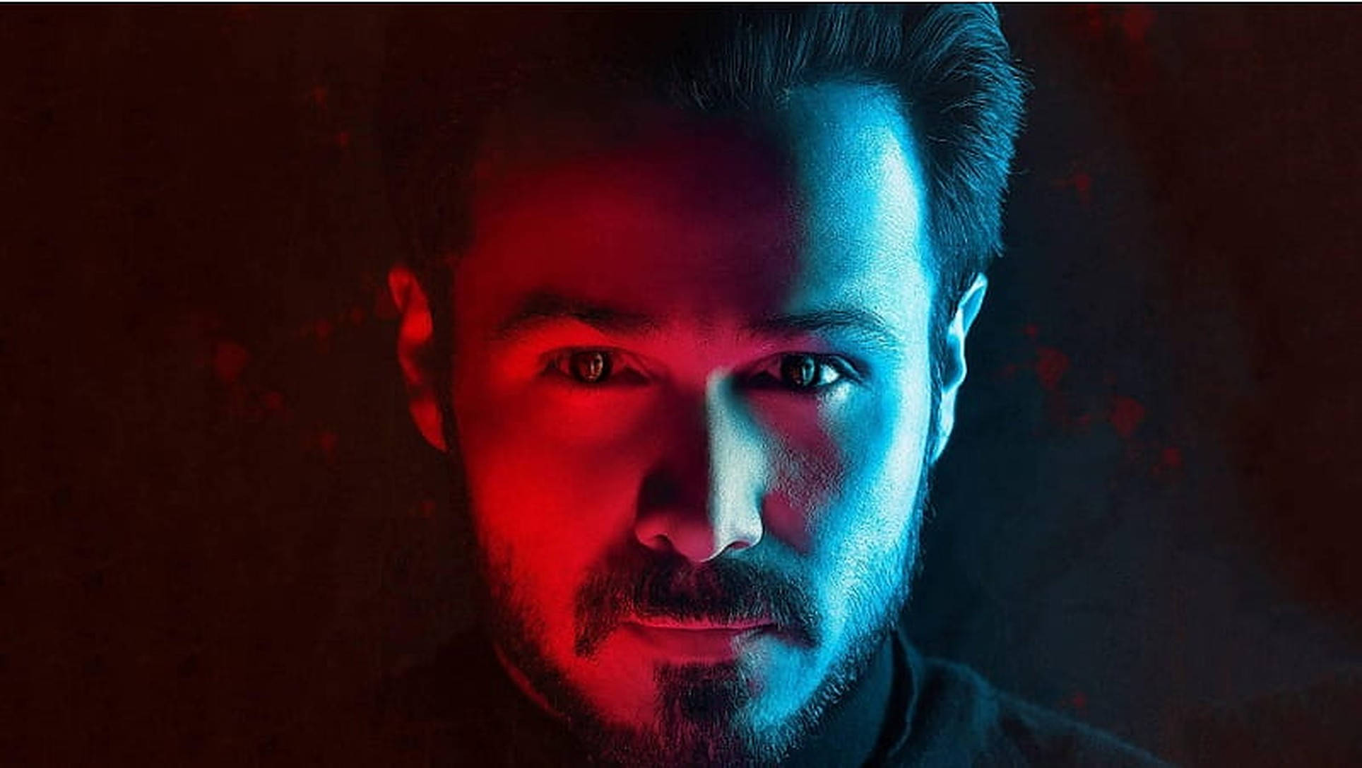 艾瑪恩·哈希米《Raaz Reboot》海報 壁紙 — 一個男人強烈的臉龐被戲劇性的紅色和藍色燈光分割，背景為深色紋理。