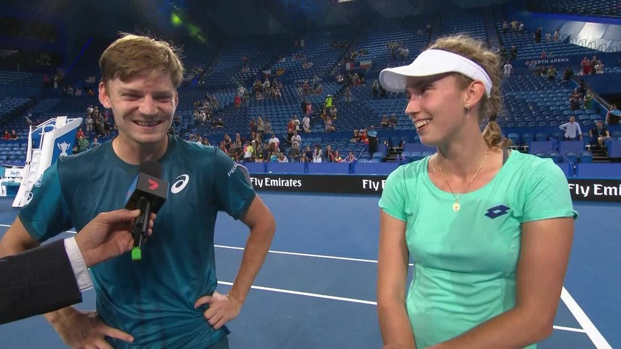 艾莉斯·梅爾騰斯與大衛·高夫曼 壁紙 — 兩位微笑的網球選手在藍色硬地球場上接受訪問時聊天，背景有觀眾。
