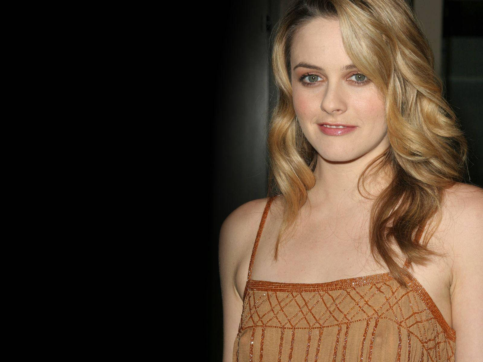 金髮綠眼女性，身穿橙色珠飾連衣裙。