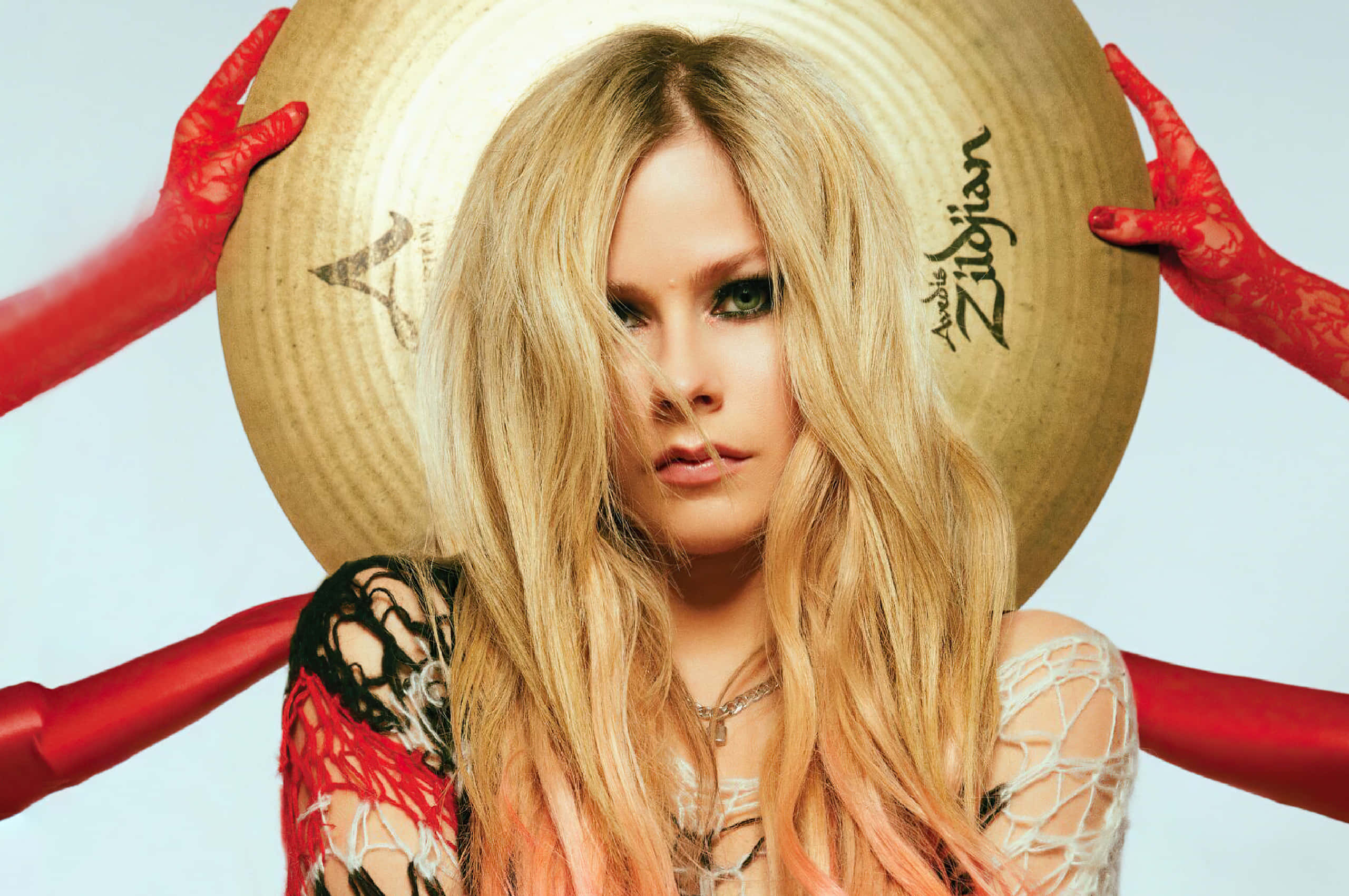 艾薇兒·拉維尼以黑粉經典造型展現強勢氣場 壁紙 — Avril Lavigne 穿著蕾絲服裝和紅色手套，將一個大型 Zildjian 鈸舉在頭後，眼神專注。