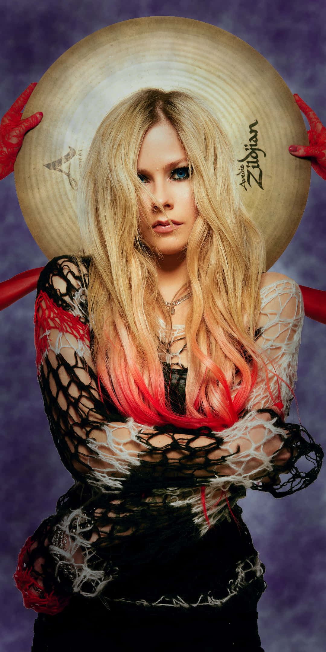 艾薇兒·拉維尼現場舞台演出 壁紙 — Avril Lavigne 強烈凝視，長長的金髮漸變為紅色，由戴著紅色手套的手拿著一個大鈸框住，背景為紫色。