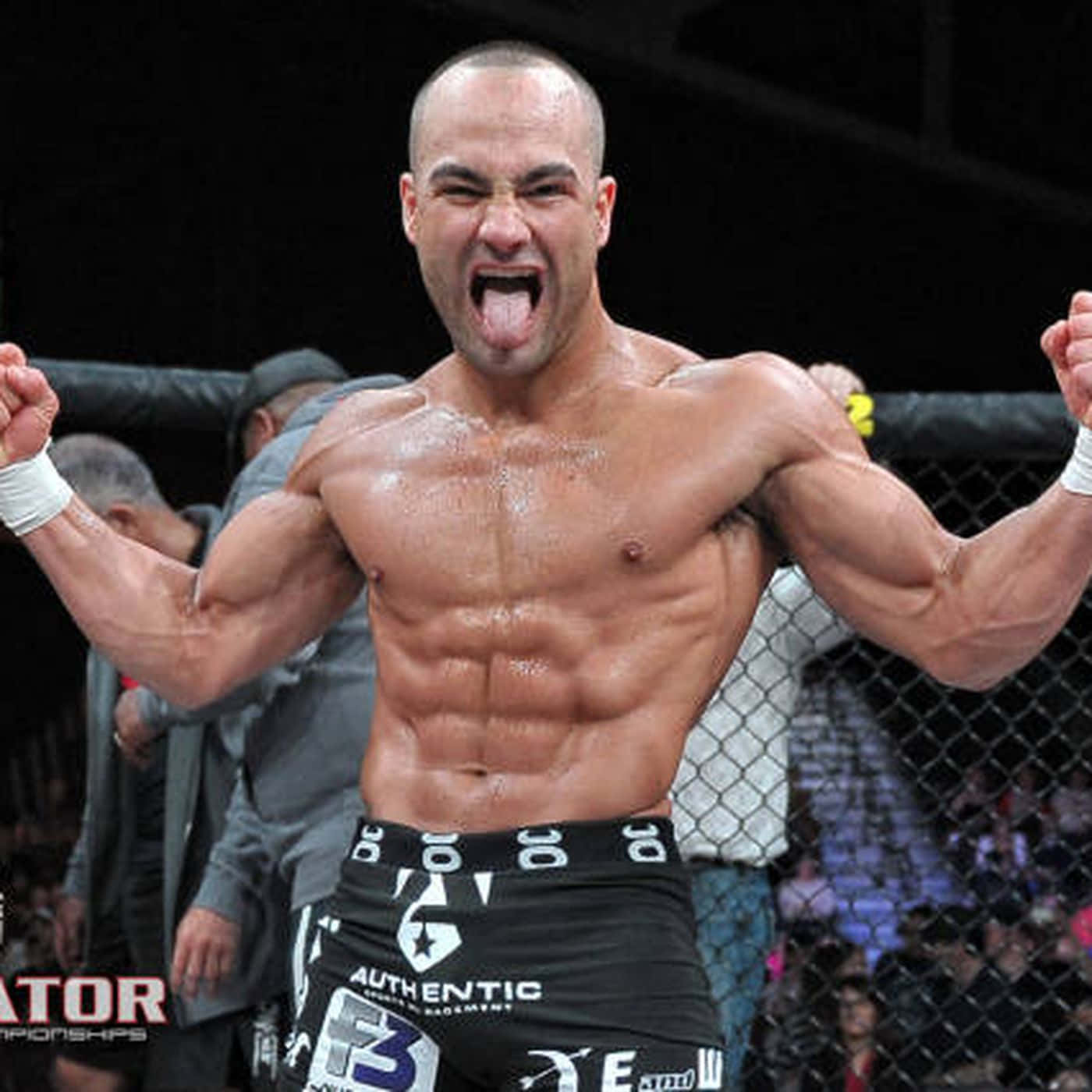 肌肉發達的拳手在MMA籠中高舉拳頭、伸出舌頭慶祝勝利。