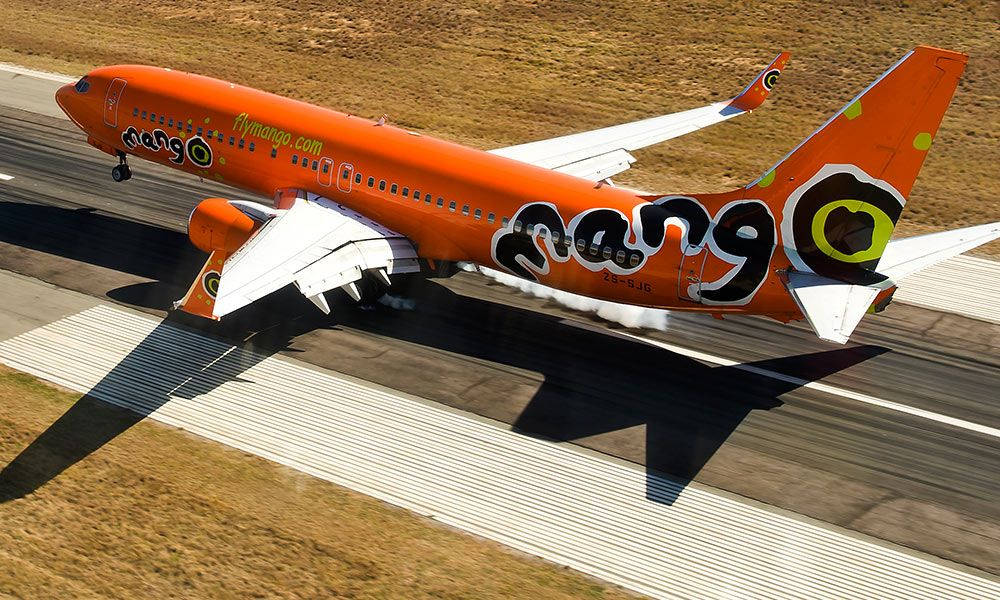 橙色Mango Airlines噴射機從跑道起飛，可見排氣同陰影。