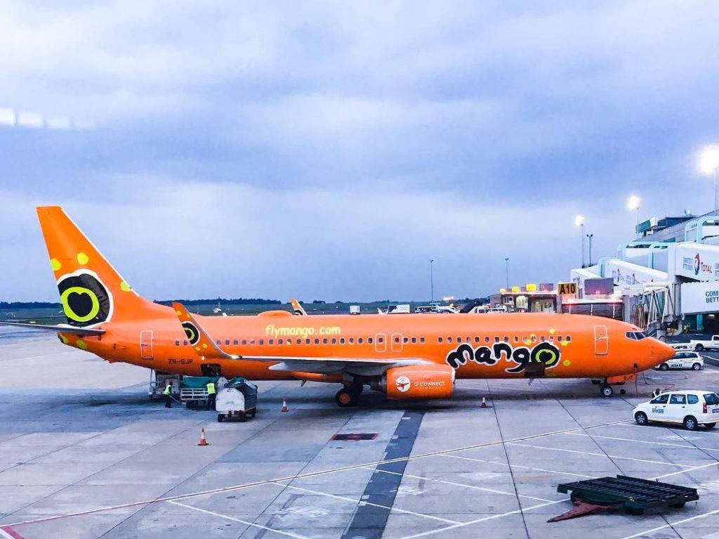 黃昏時分，橙色Mango Airlines飛機停泊在機場閘口。