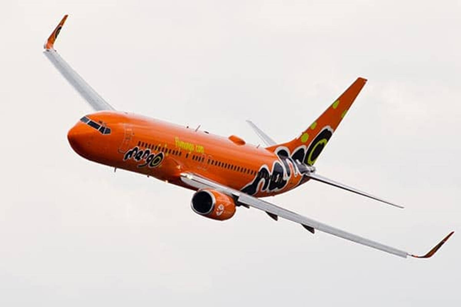 橙色Mango Airlines飛機在陰天飛行。