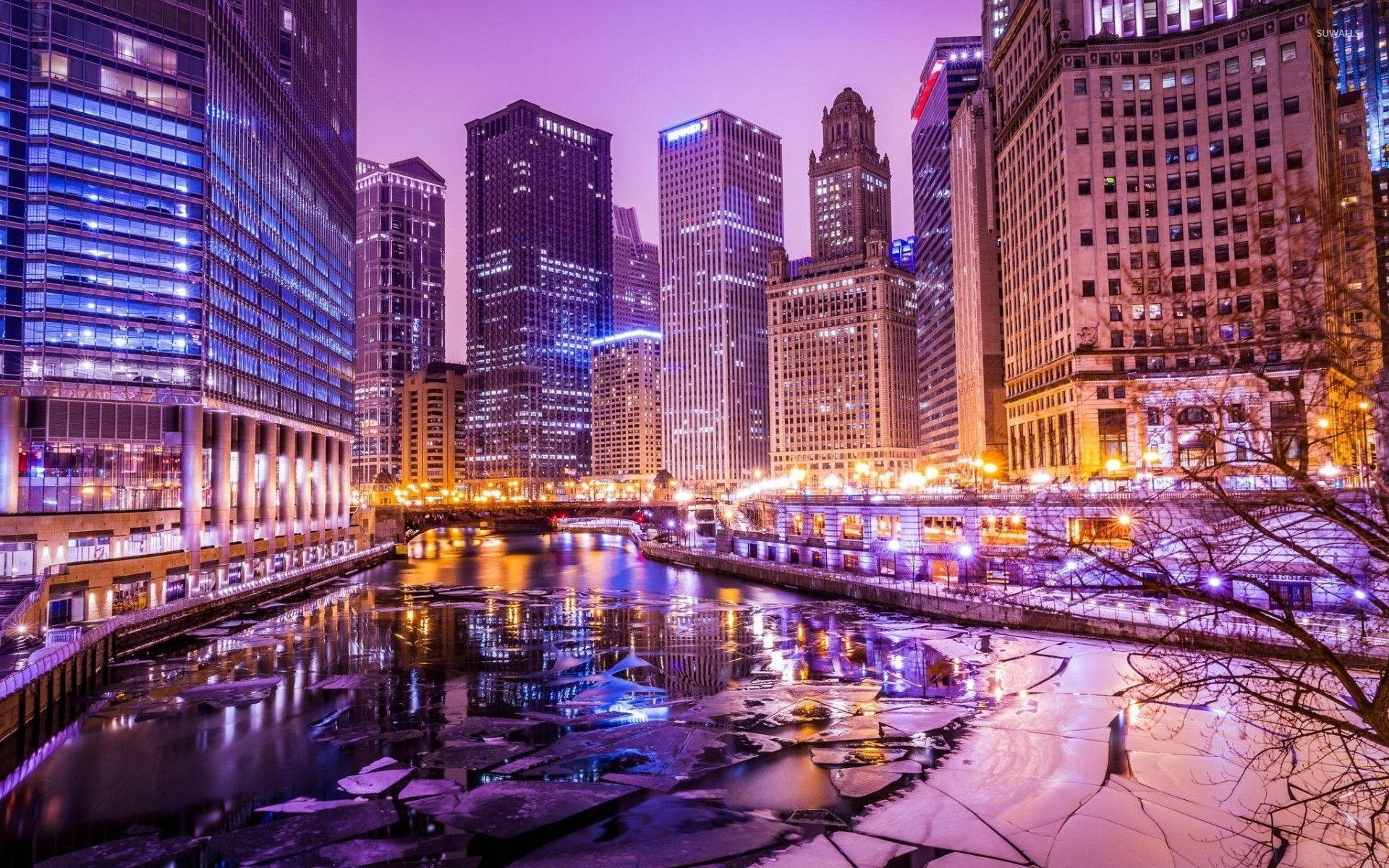 夜晚的城市天際線，燈火通明的建築物倒映在結冰的河流中。