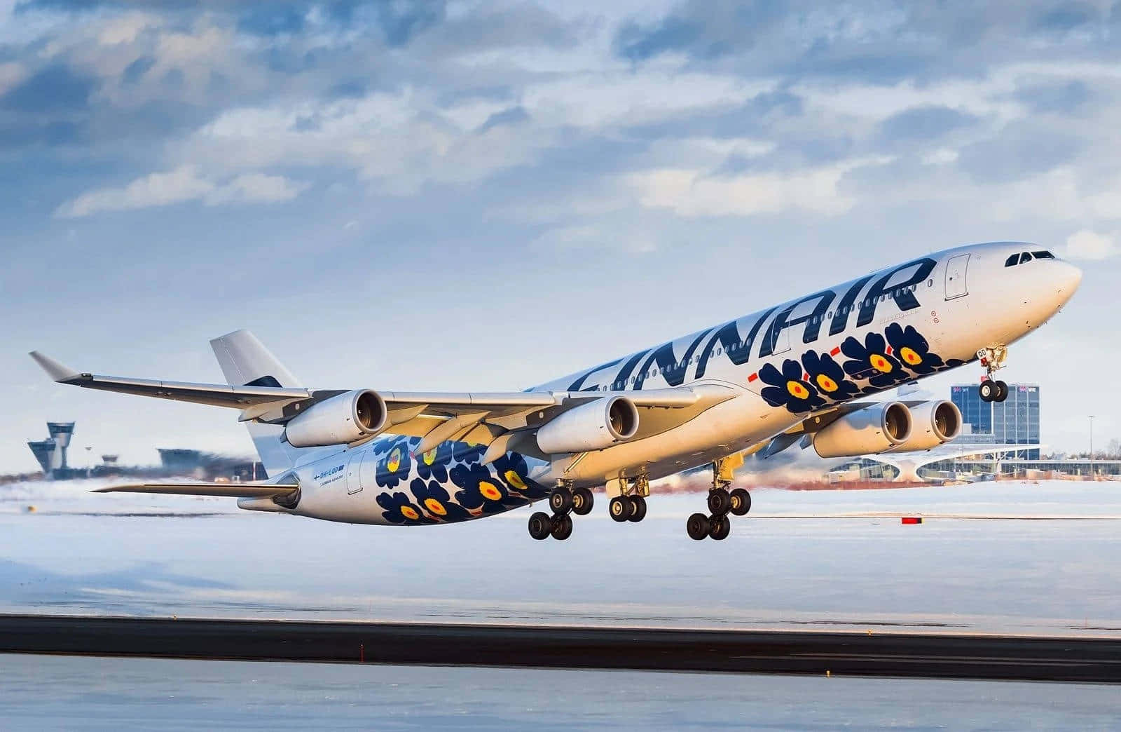 芬蘭航空A340冬季離港 壁紙 — 芬蘭航空 Airbus A330 花卉塗裝飛機在陰天從積雪跑道起飛。