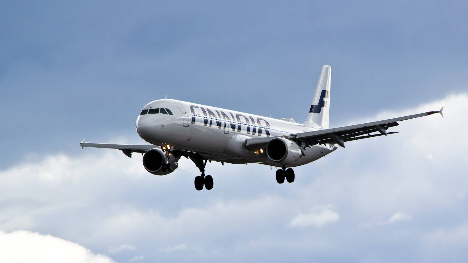 芬蘭航空飛機在藍天白雲下接近降落。