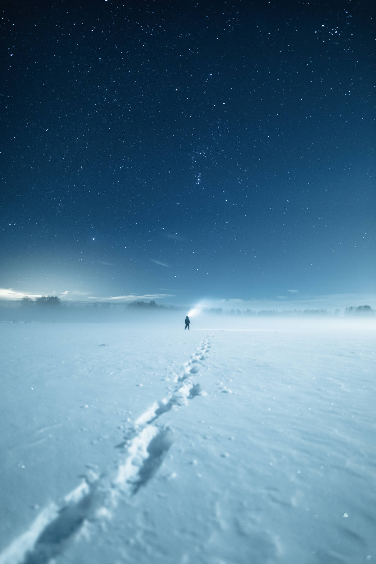一個人在星空下的雪地中獨自行走。