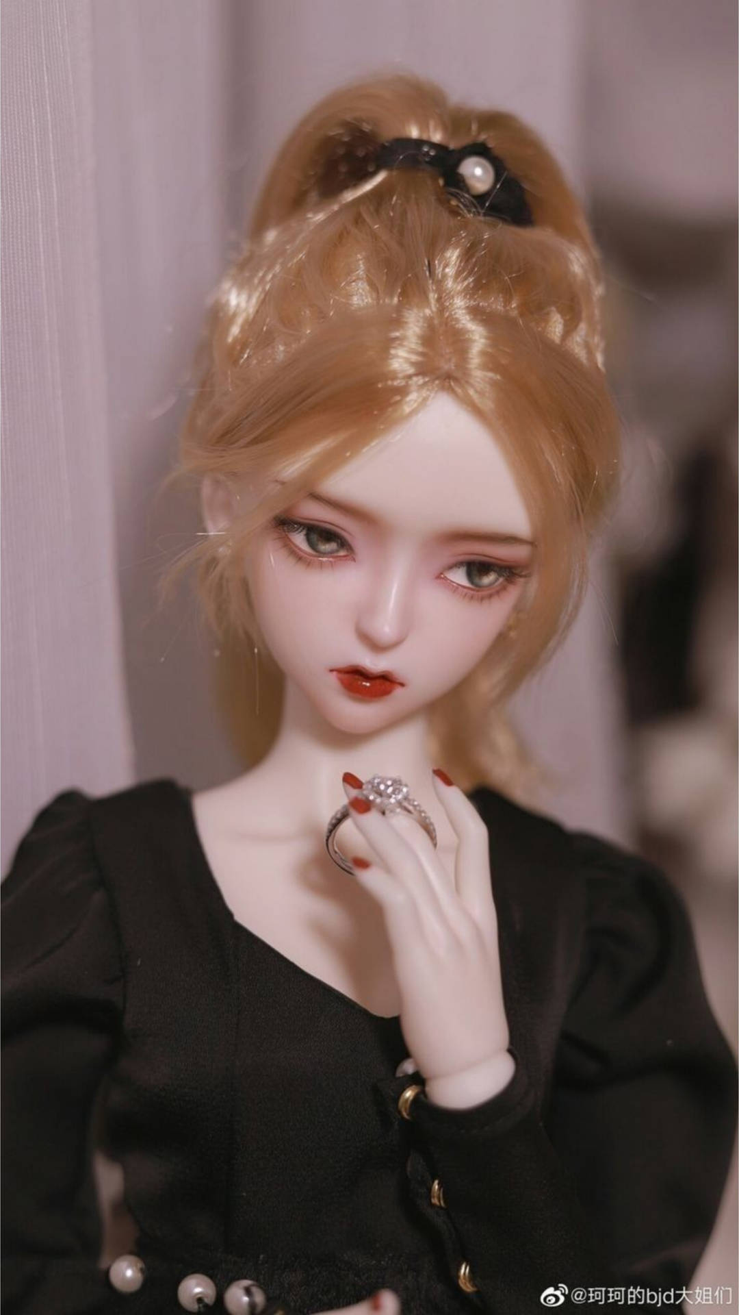 一個金色頭髮和黑色連衣裙的娃娃拿著戒指。
