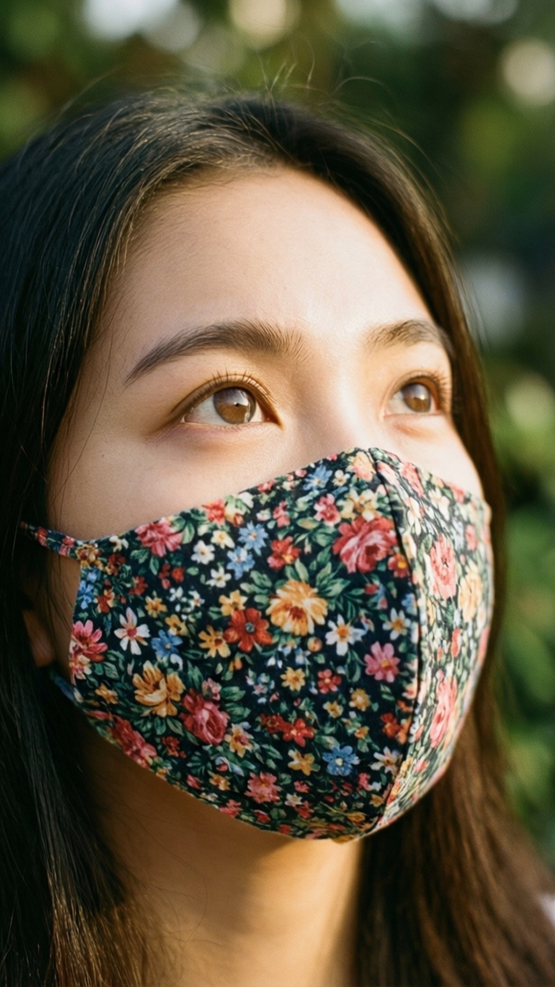 年輕女性戴著花卉口罩在陽光下向上仰望