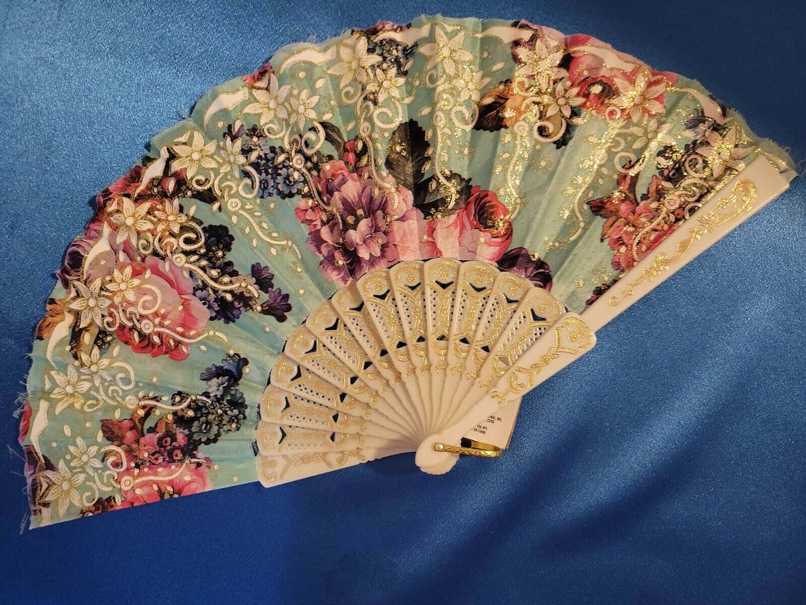 一把在藍色布料上帶有金色點綴、刺繡精緻的手扇。