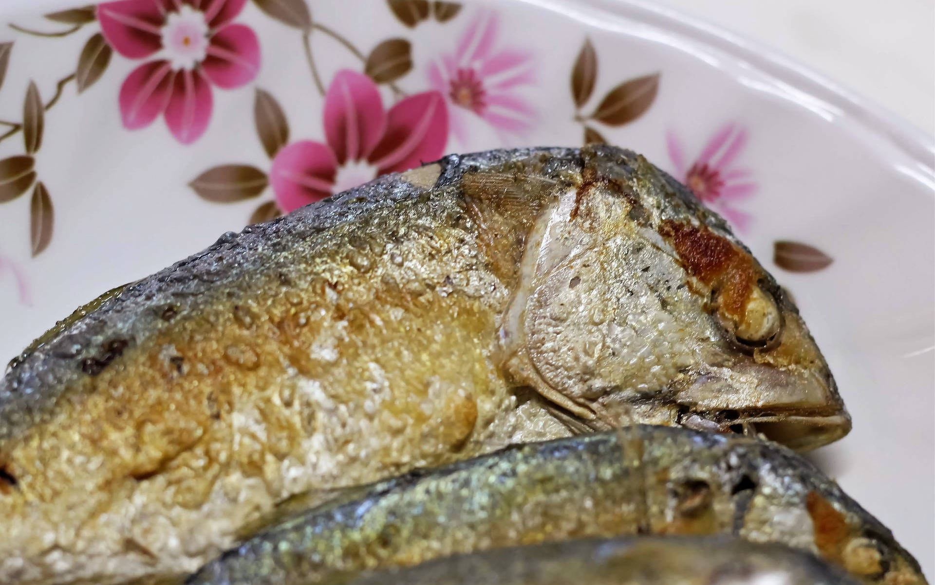 花卉盤盛裝的炸海 bass 壁紙 — 金黃酥脆的炸魚放在花卉圖案的碟子上。