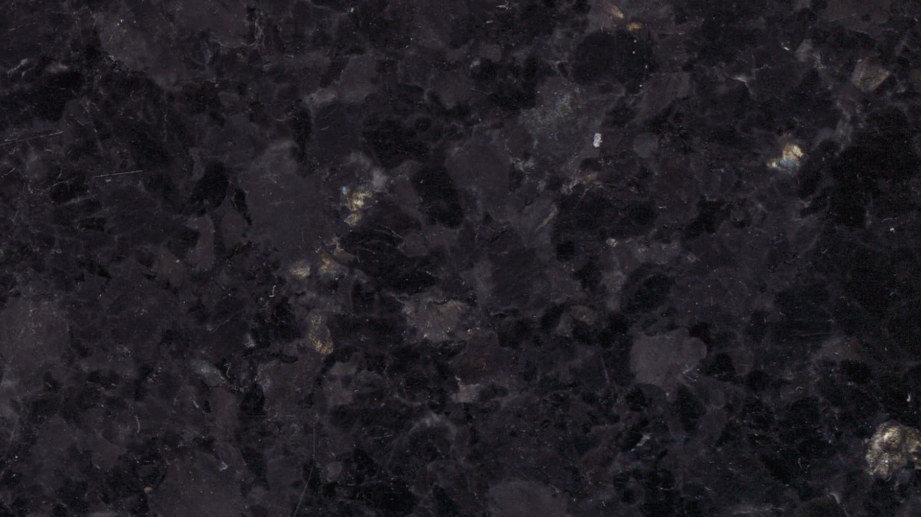 帶有金色斑點和礦物圖案的深色花崗岩表面。