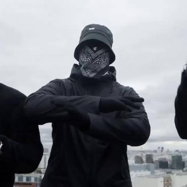 身穿黑色街頭服飾和頭巾的人，在灰色天空下的城市天台