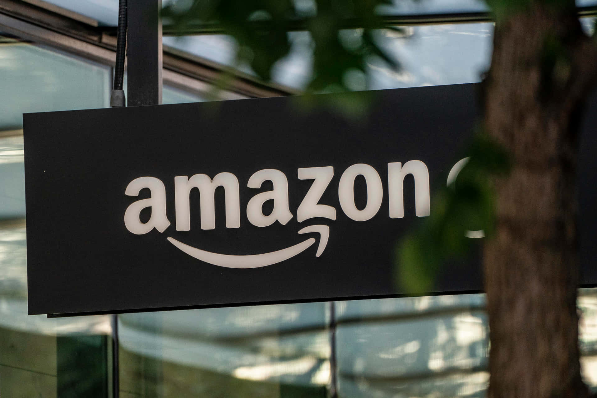 透過玻璃建築附近的樹葉看到的Amazon標誌